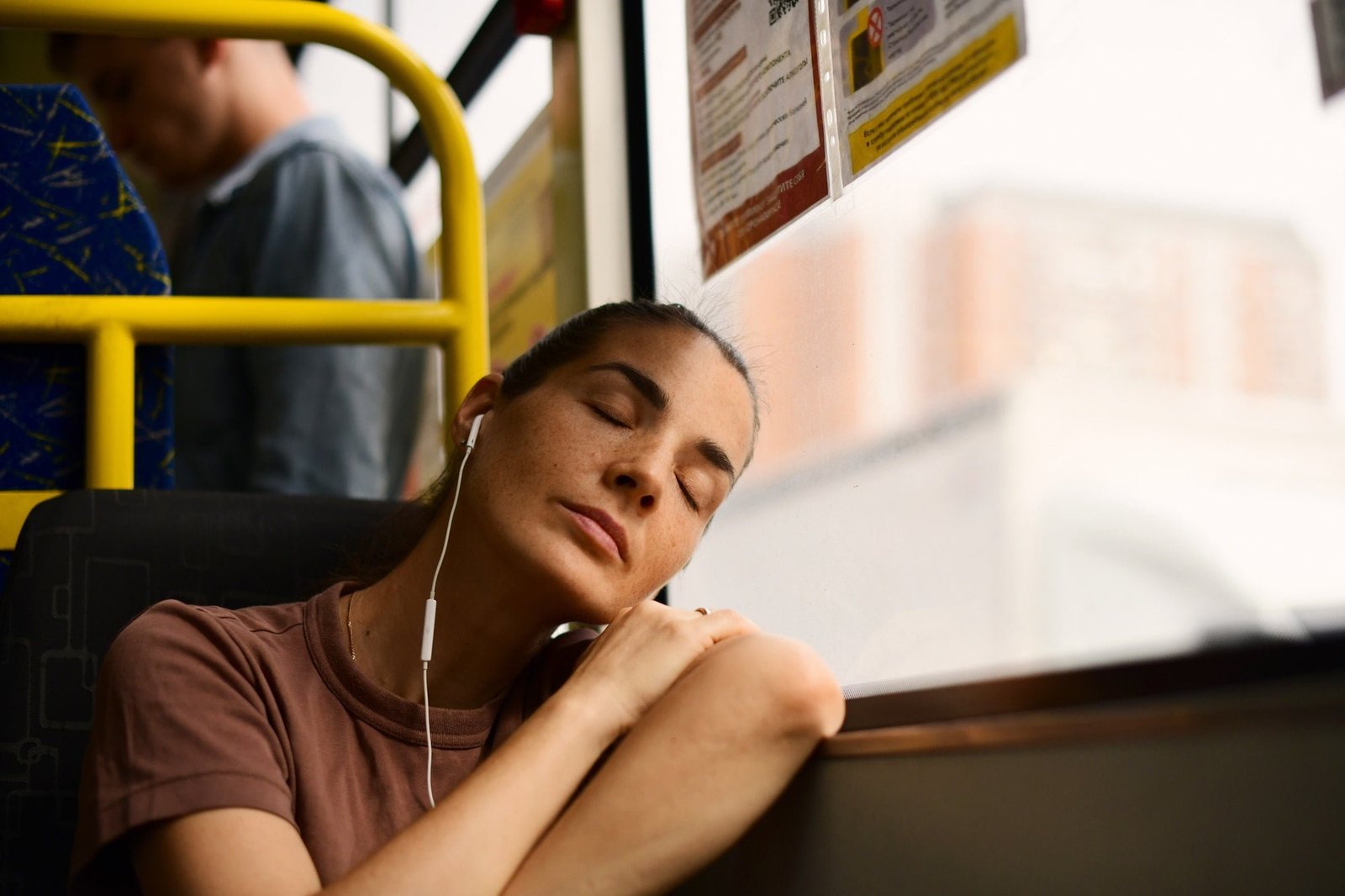 A young beautiful woman is sleeping at the bus window, A tired bus passenger is going home